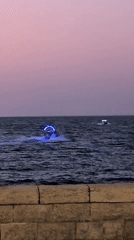 Tel Aviv at dusk: jet ski on water, clock tower lit up