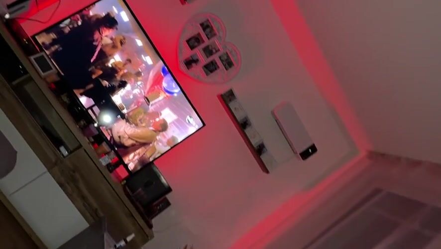 Late-night television viewing captured in red-lit Bad Bellingen room