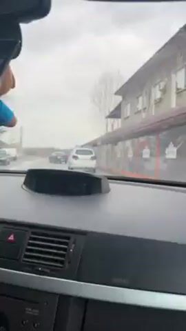 The video, shot from inside a car driving on a rainy day, shows a "Gendarmerie" vehicle, likely a police car, in front. The dashboard display reads 16:33, 15 degrees Celsius, and 90.5. The wipers are in motion, clearing the rain from the windshield. A small Bulgarian flag is visible on the passenger side of the dashboard. A voice in the background speaks in a language other than English.