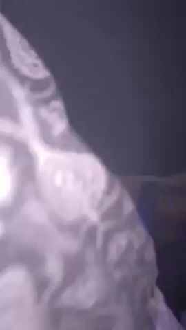 The video shows a crowd of people at a club or concert. The lighting is dark, with purple lights illuminating the stage. There is a lot of smoke or haze in the air, making it hard to see clearly. Some people are dancing and moving to the music. The camera moves around, showing different parts of the crowd and stage.