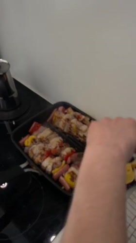 Person cooks meat and vegetable skewers in Milan kitchen