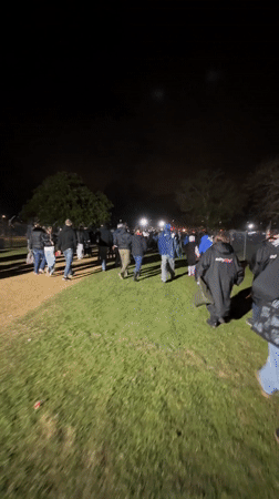 Large group walks toward light source in Norwich field