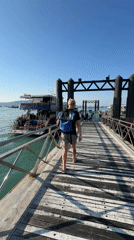 Tourist walks pier among dive boats in Rawai harbor