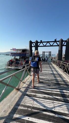 Tourist walks pier among dive boats in Rawai harbor