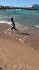 Boy runs along Egyptian beach as yacht docks at pier
