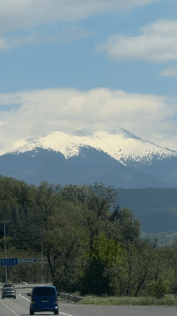 Snow-capped mountain viewed from Bulgarian highway under clear skies