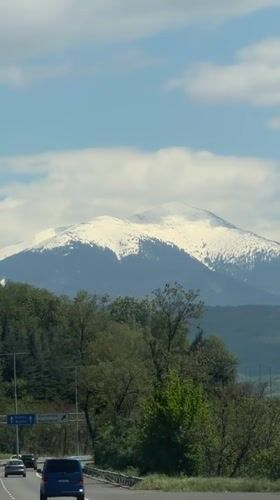 Snow-capped mountain viewed from Bulgarian highway under clear skies