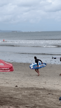 Early morning beach activity and worker break captured in Kuta