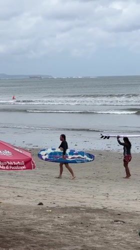 Early morning beach activity and worker break captured in Kuta