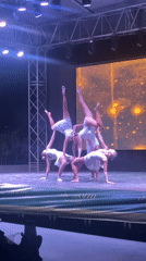 Acrobatic pyramid routine on a spotlit stage in Kemer