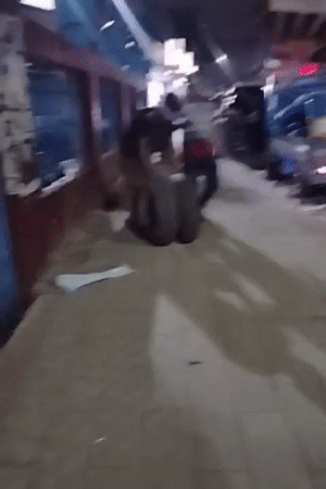 Hauling large tires along a busy Dhaka sidewalk at night