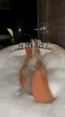 Person Takes Bubble Bath in White Modern Tub