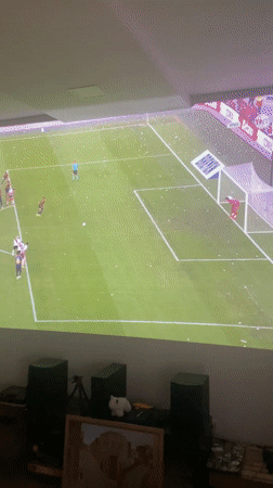 Young men watch soccer penalty kick on backyard projector