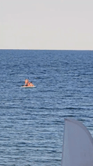 Group on a paddleboard, orange vests, calm open ocean