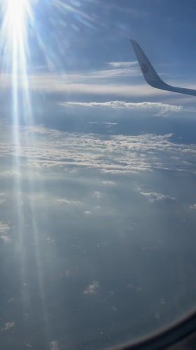 Passenger films sunlit cloudscape from airplane over Guanghan City