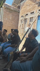 Casual outdoor gathering under a canopy near a blue house