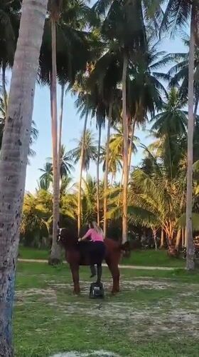 Woman horseback rides at tropical Thai beach during morning