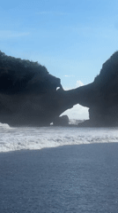 Man stands in ocean at Indonesian black sand beach
