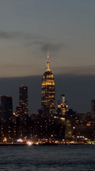 Nighttime NYC skyline view features illuminated Empire State Building