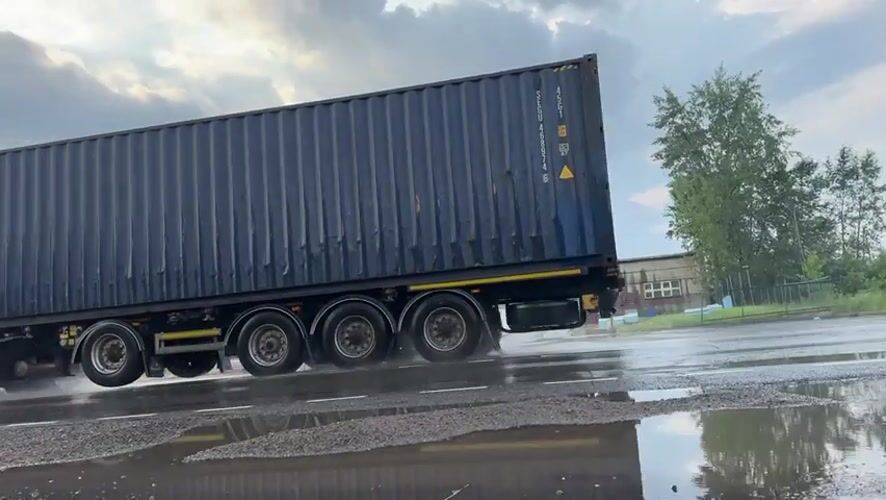 Trucks move through Beryozovka under a stormy sky