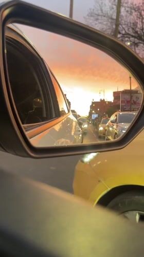 Marrakesh driver captures sunset in side mirror during evening traffic