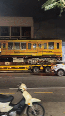 Yellow subway car transported on flatbed through Buenos Aires streets