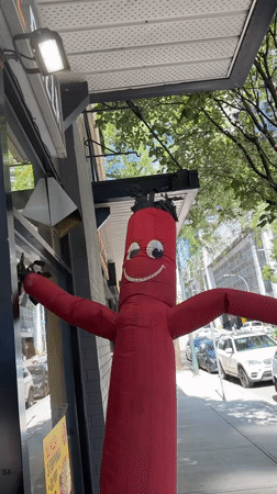 Inflatable tube man and glass towers on a New Westminster street