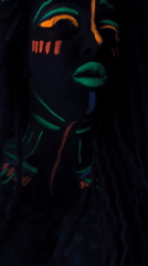 Woman displays neon face paint under blacklight in Noviy