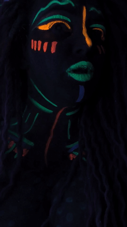 Woman displays neon face paint under blacklight in Noviy