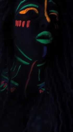 Woman displays neon face paint under blacklight in Noviy