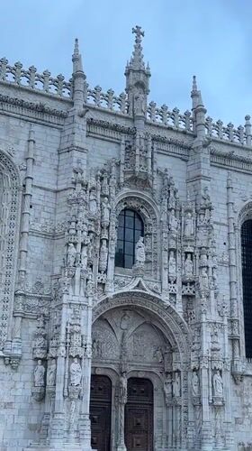 Exploring Jerónimos Monastery's Manueline architecture on a cloudy evening
