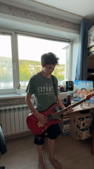 Boy plays red electric guitar indoors in Mezhdurechensk