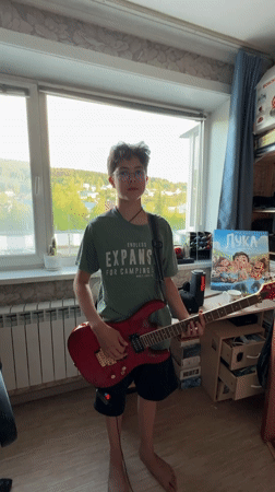 Boy plays red electric guitar indoors in Mezhdurechensk