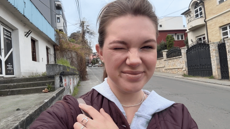 Woman with bag stands on sidewalk in Belgrade suburb