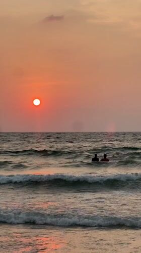 Two people enjoy ocean sunset at Choeng Thale beach