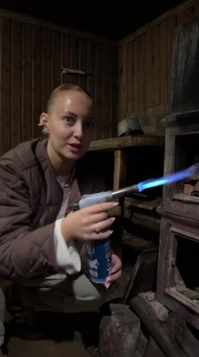 Woman lights old cast iron stove in rural Russia