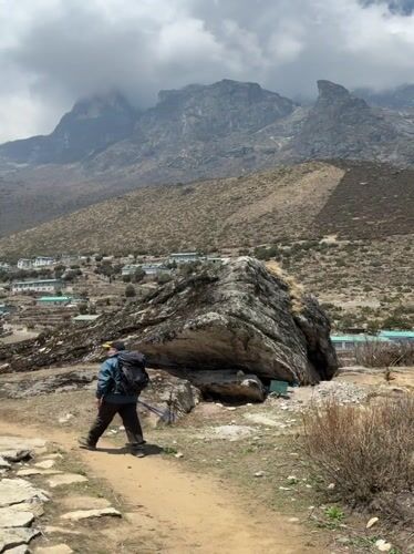 Trekker approaches Khumjung village in Nepal mountains