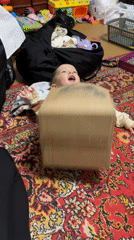 Toddler plays with box as spiders appear on clothesline