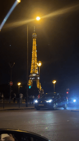 Evening scene captured at illuminated Eiffel Tower with pedestrian activity