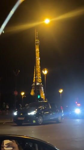 Evening scene captured at illuminated Eiffel Tower with pedestrian activity