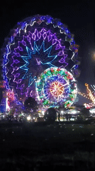 Nighttime carnival with illuminated Ferris wheels operates in Titibaro, Indonesia