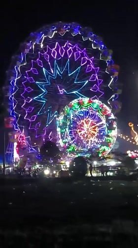 Nighttime carnival with illuminated Ferris wheels operates in Titibaro, Indonesia