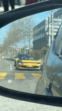 Yellow sports car stops at Zurich crosswalk during midday traffic