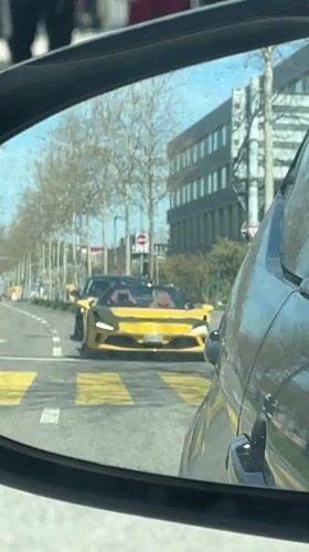 Yellow sports car stops at Zurich crosswalk during midday traffic