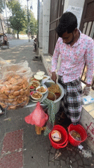 Street vendor serves fried food from sidewalk in Dhaka