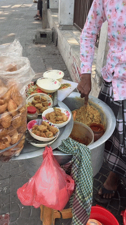 Street vendor serves fried food from sidewalk in Dhaka