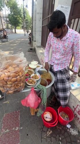 Street vendor serves fried food from sidewalk in Dhaka