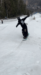 Snowboarder performs tricks at terrain park in early morning