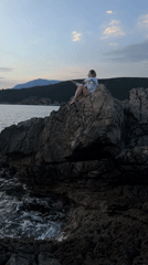 Woman takes selfies on Montenegro coastline during sunset