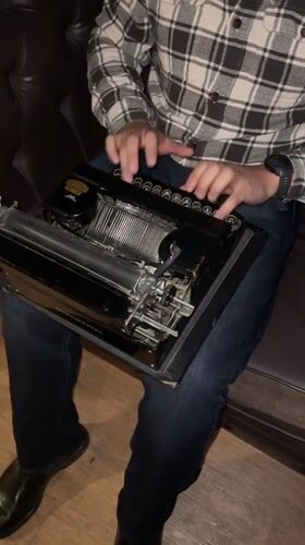 Person uses vintage typewriter on couch in Bogota